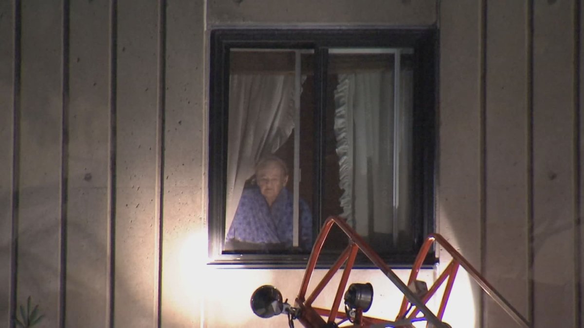 A woman looks out her window after a Côte-des-Neiges apartment building fire on the early morning of May 30, 2022.