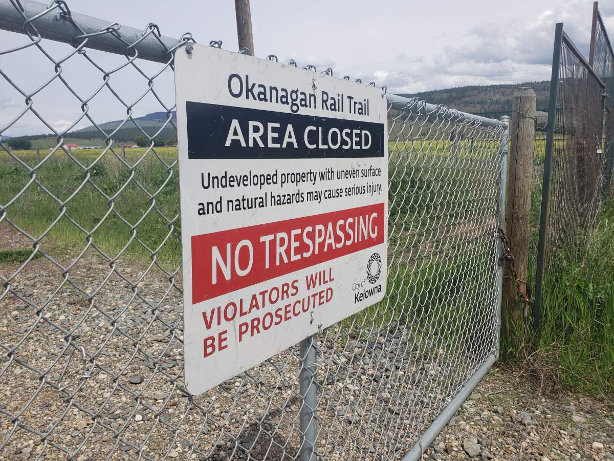 The Okanagan Rail Trail from Coldstream to Kelowna remains unfinished and blocked off north of the Kelowna airport. A sign warns trespassers will be prosecuted.