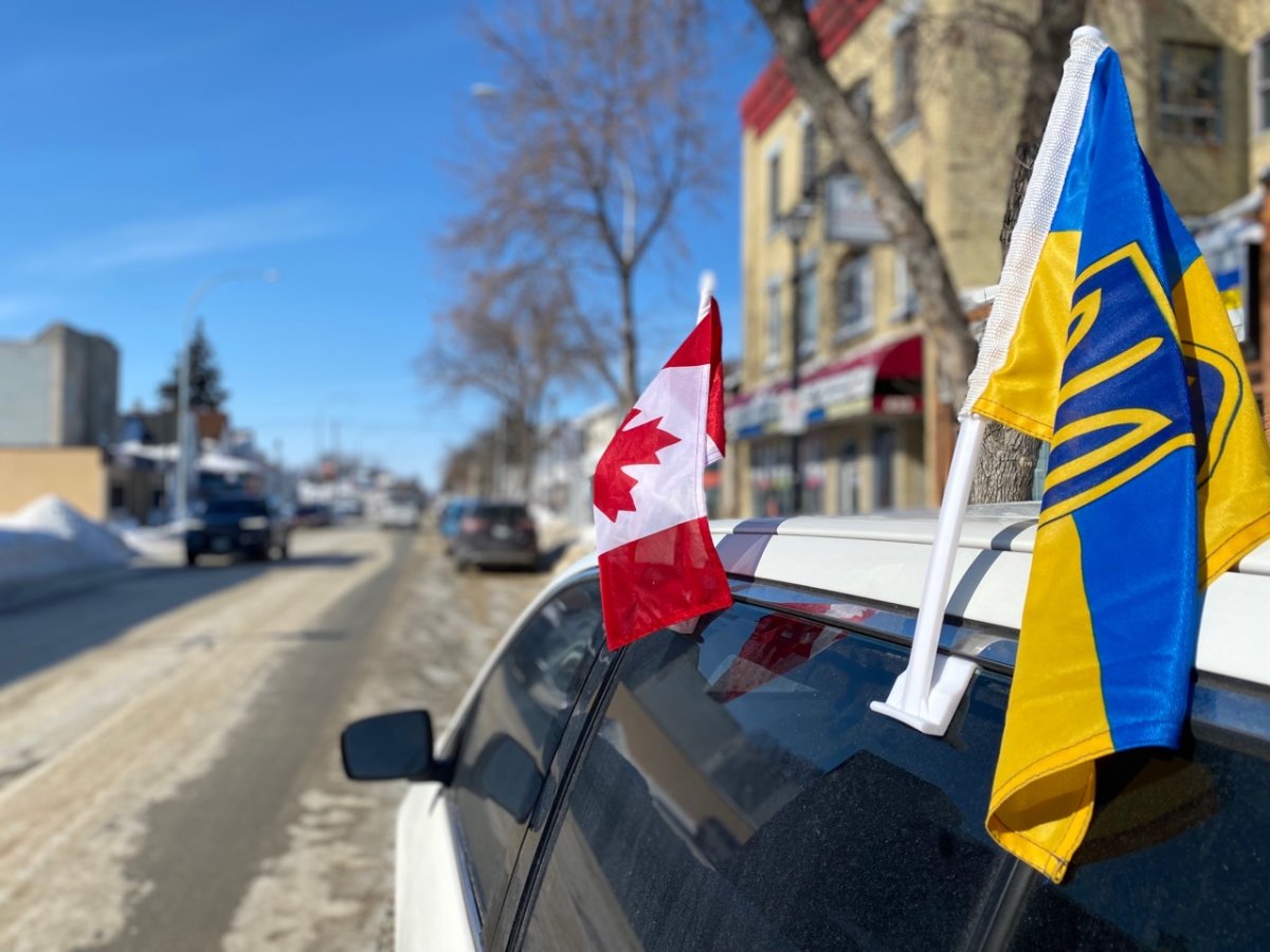 Ukrainian and Canadian flags fly on a vehicle.