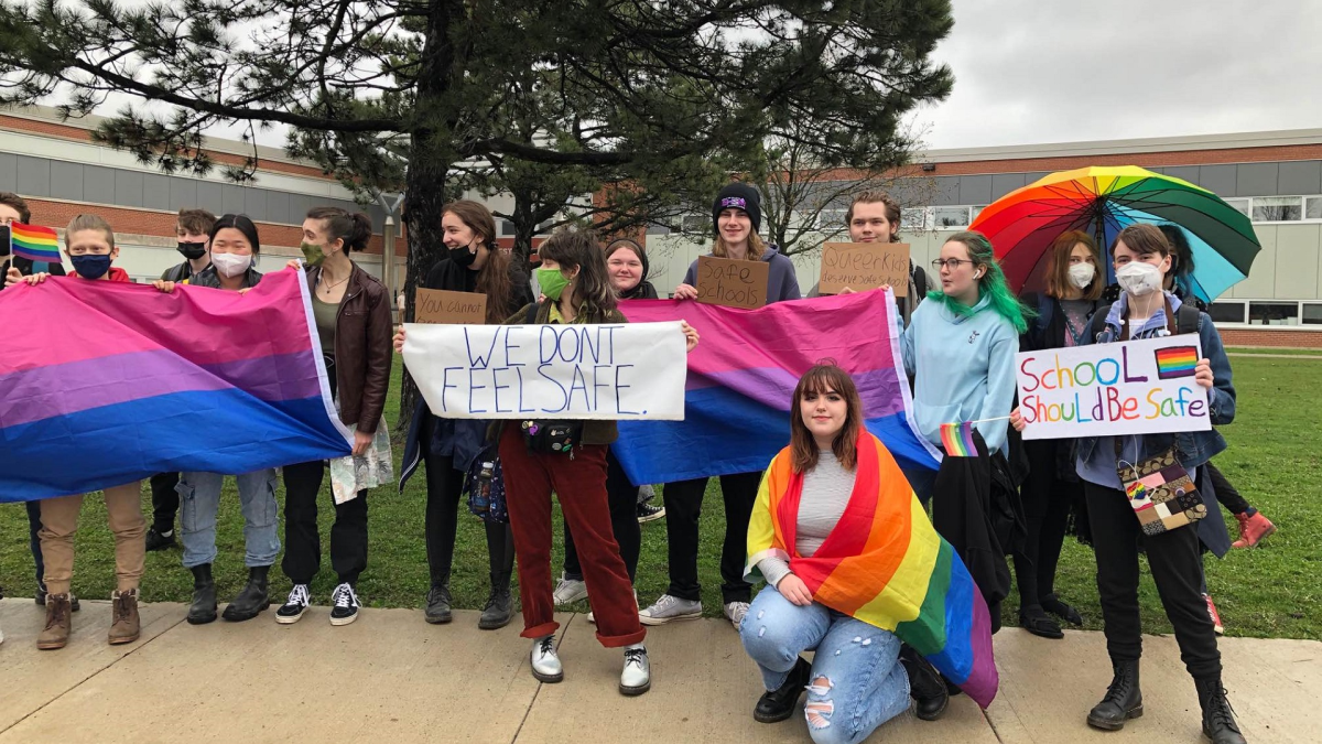 Westmount students rally in front of their school, holding Pride flags and signs