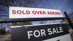 A 'for sale' sign on Canadian real estate advertises that it was sold over the asking price.