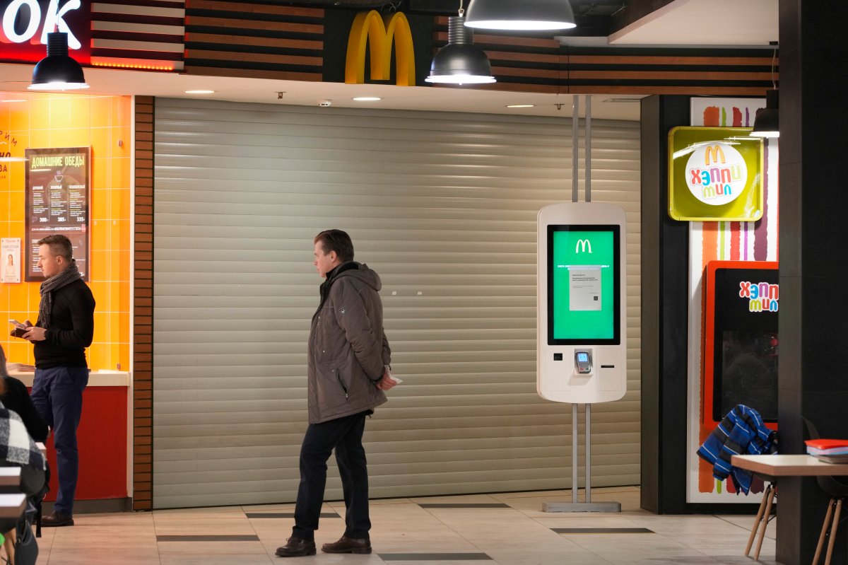 A man stands next to a McDonald's restaurant closed to visitors at a mall in St. Petersburg, Russia, Tuesday, March 15, 2022. (AP Photo).