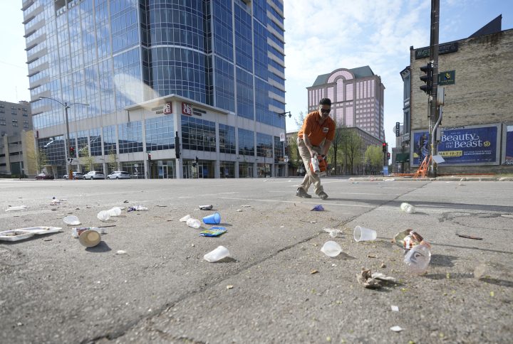 Victor Prado, with MKE Downtown, clears debris near the corner of North Water Street and East Juneau Avenue in Milwaukee, Saturday, May 14, 2022, where multiple people were shot and injured late Friday in Milwaukee’s downtown bar district after the Milwaukee Bucks playoff game.