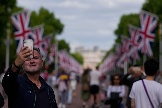 A tourist takes a photo in front of flags strewn in the streets in front of Buckinham Palace for the Platinum Jubilee.