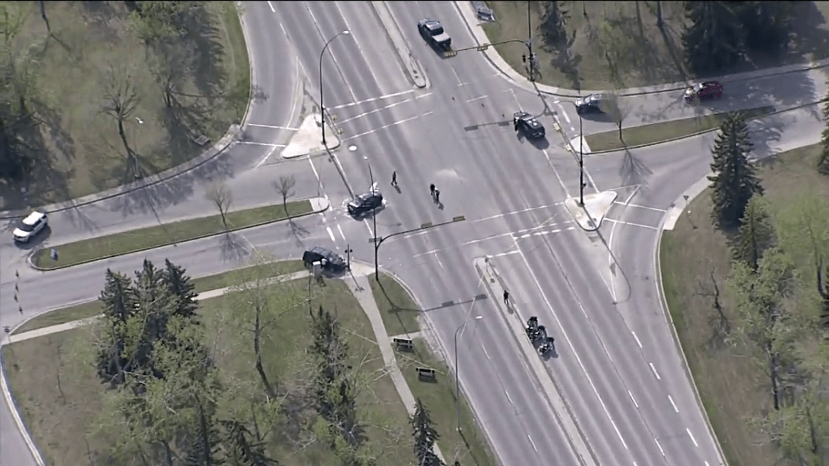Calgary police investigate a collision involving two vehicles and a cyclist at Canyon Meadows Drive S.E. and Lake Crimson Drive S.E. on May 26, 2022.