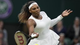 Serena Williams plays tennis in a white outfit.