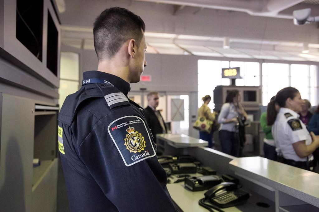 A Canadian Border Services agent stands watch at a gate on Tuesday, December 8, 2015. 