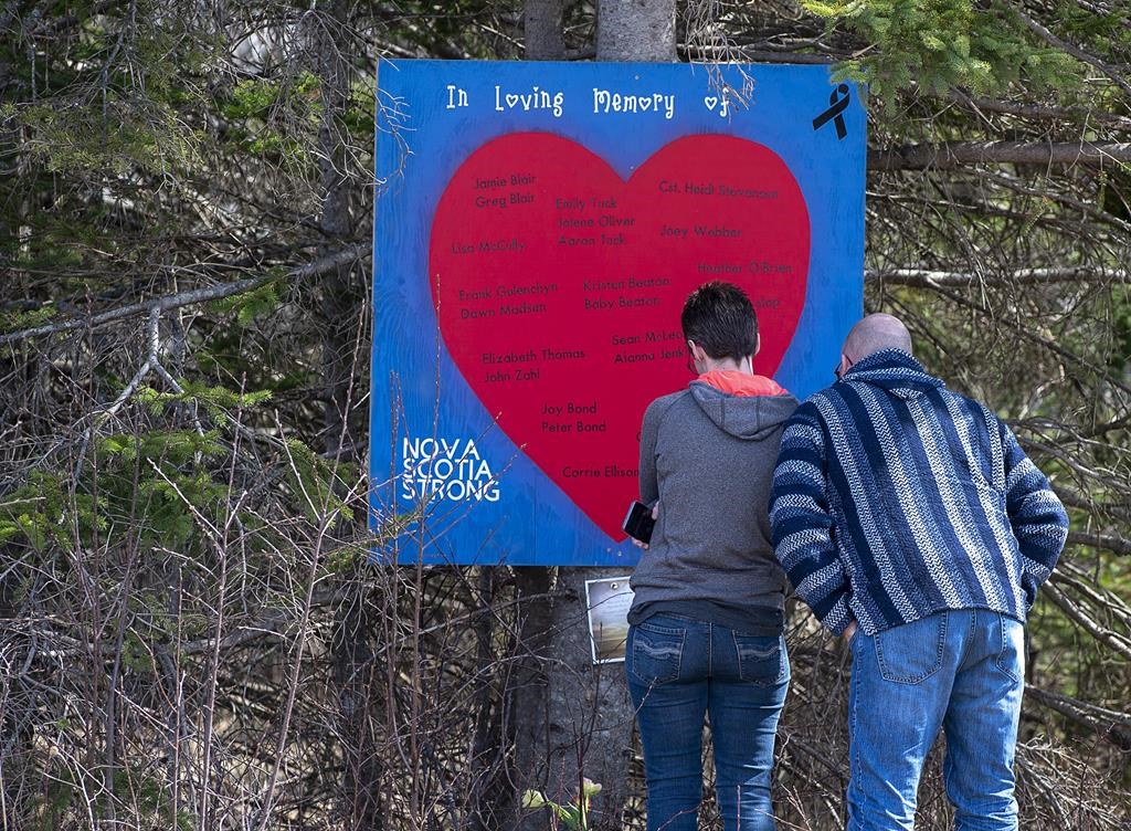 People pay their respects at a roadside memorial in Portapique, N.S. on Sunday, April 26, 2020. Nova Scotia Premier Tim Houston is asking people to pause for a moment of silence today at noon and again on Wednesday to remember the 22 lives lost. THE CANADIAN PRESS/Andrew Vaughan.