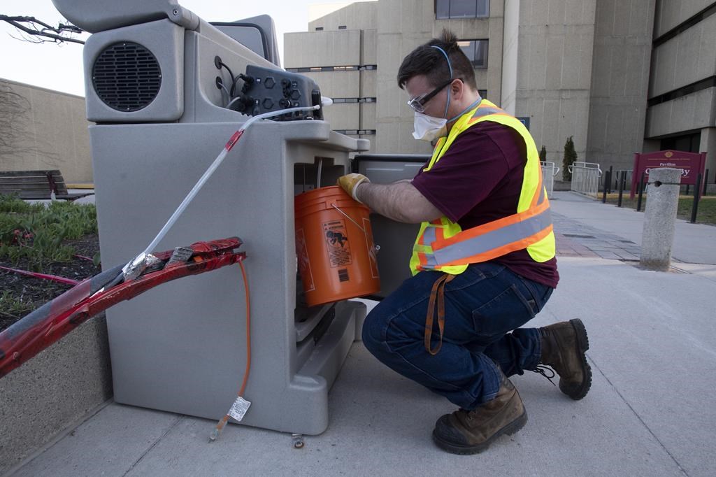 Student Patrick D'Aoust places a wastewater collection container inside a pump station used to collect wastewater samples that are screened for COVID-19 at the University of Ottawa campus on April 8, 2021 in Ottawa. Quebec has been screening wastewater for COVID-19 in Quebec City and the Montreal area since late March, but only began releasing the data today. 