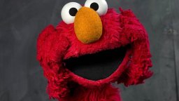 Elmo is seen with his hands to his face. He looks surprised or shocked.