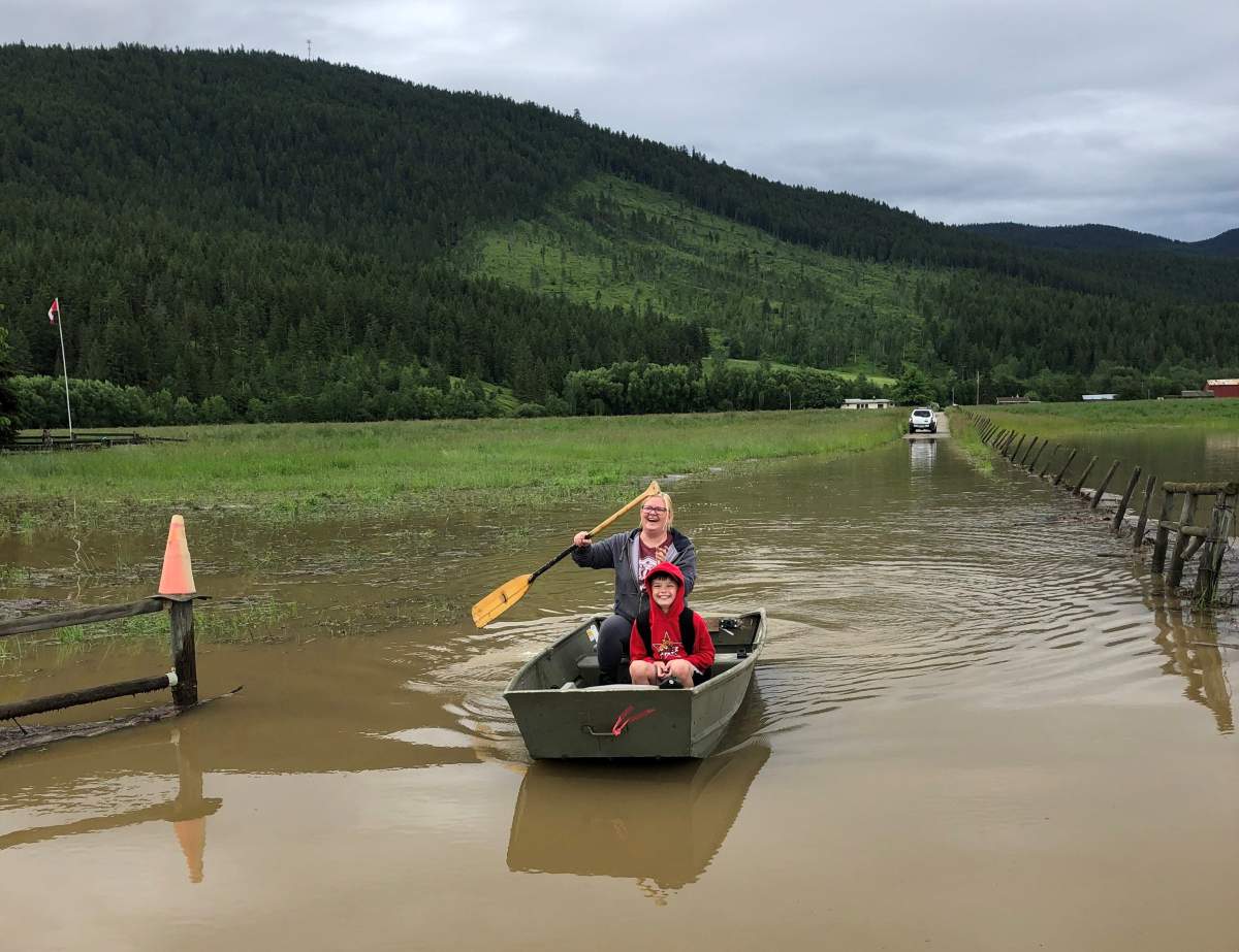 Student Haiden Smithson and his mother Haili Valin boat part of the way to school after a nearby creek burst its banks and flooded the Whitevale Rd. area near Lumby. Photo Courtesy: Sherry Heath