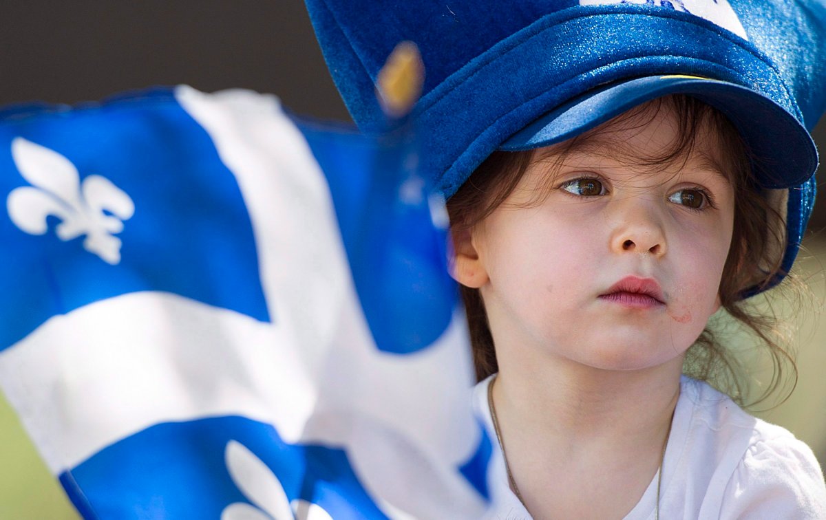 A young girl holds a Quebec flag as she watches the annual Saint-Jean-Baptiste day parade in Montreal, Saturday, June 24, 2017. 