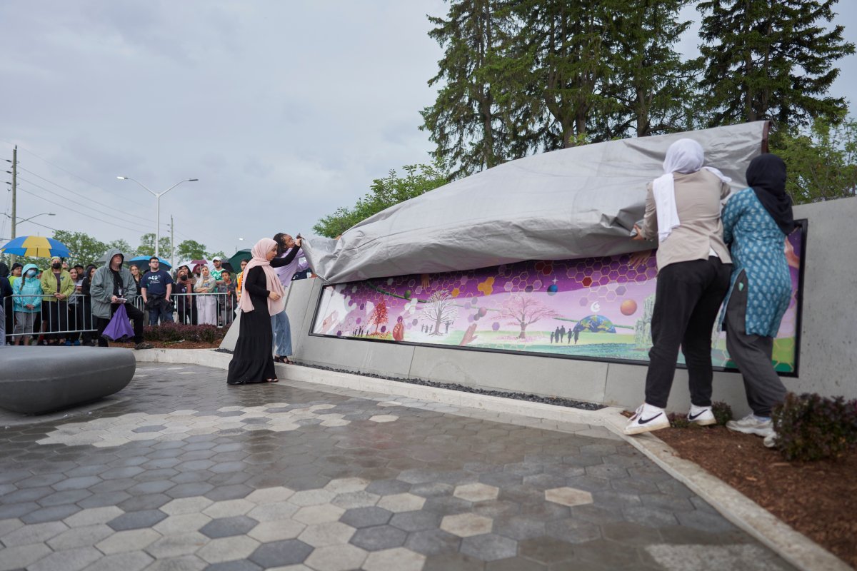 Friends of Yumnah Afzaal unveil a mural at a vigil for the Afzaal family in London, Ont., Monday, June 6, 2022.