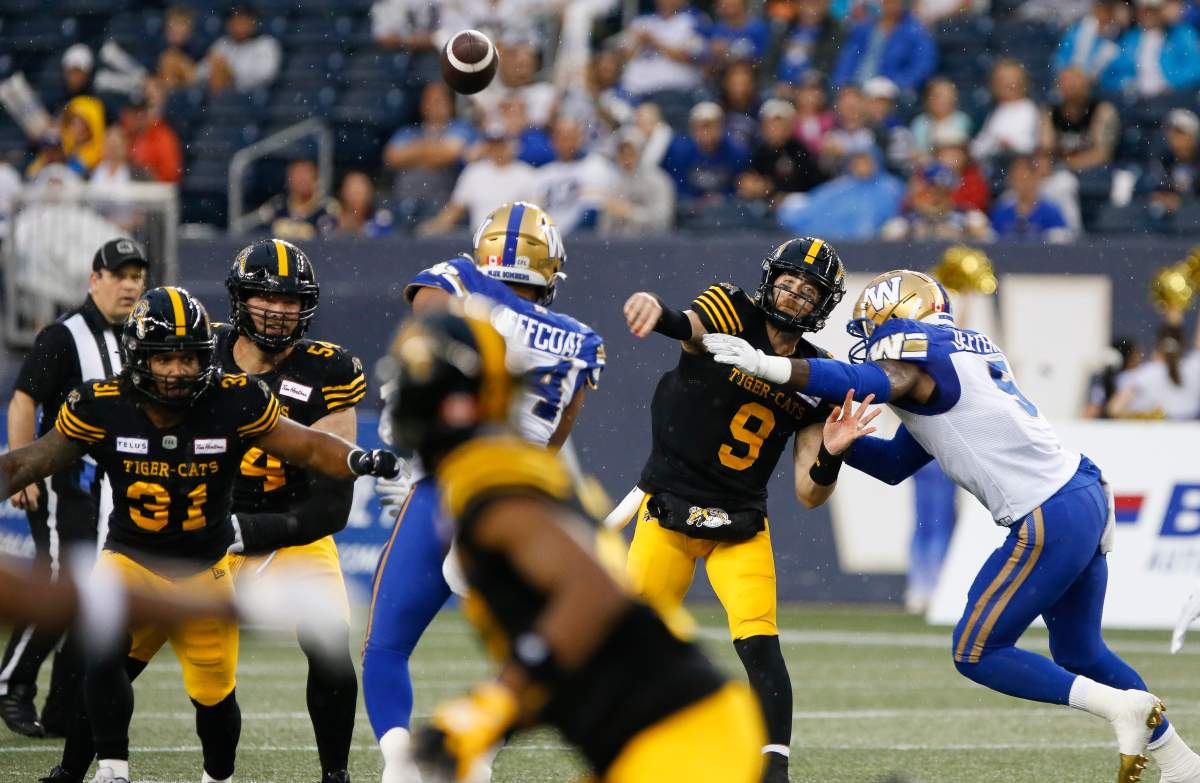 Hamilton Tiger-Cats quarterback Dane Evans (9) gets the throw away despite pressure from Winnipeg Blue Bombers’ Willie Jefferson (5) and Jackson Jeffcoat (94) during the first half of CFL action in Winnipeg, Friday, June 24, 2022. JOHN WOODS/THE CANADIAN PRESS