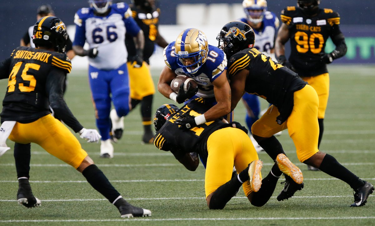 Winnipeg Blue Bombers' Nic Demski (10) gets tackled by Hamilton Tiger-Cats' Kameron Kelly (11) and Simoni Lawrence (21) during the first half of CFL action in Winnipeg.
