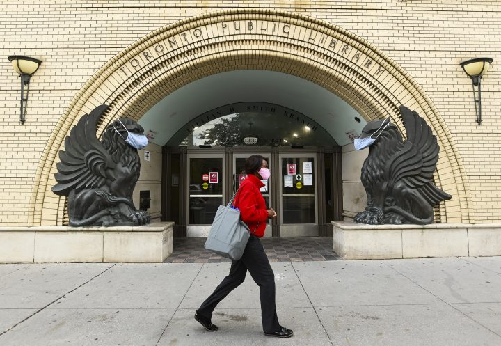 A woman walks past a Toronto Public Library . 