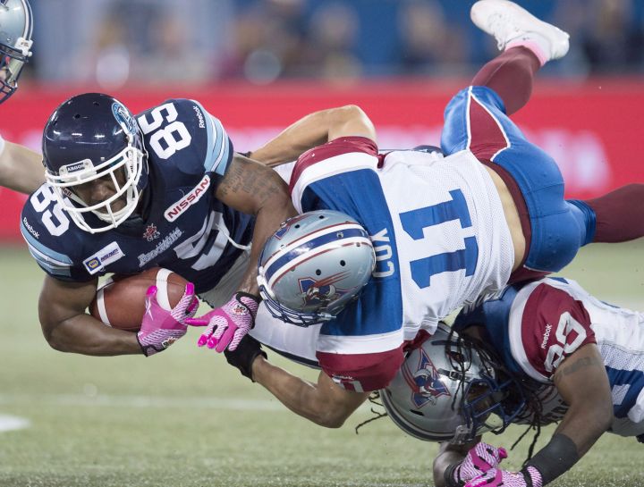 Toronto Argonauts wide receiver John Chiles (85) is tackled by Montreal Alouettes linebacker Chip Cox (11) and defensive back Jerald Brown (bottom) during second half CFL action in Toronto on Saturday October 18, 2014.