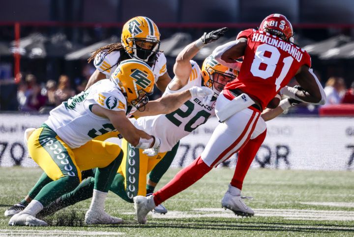 Edmonton Elks defensive back Scott Hutter, centre, grabs for Calgary Stampeders receiver Luther Hakunavanhu during first half CFL football action in Calgary, Saturday, June 25, 2022. 