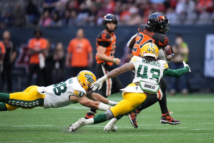 B.C. Lions' James Butler (24) avoids tackles by Edmonton Elks' Adam Konar, left, and Enock Makonzo (43) and runs for his second touchdown during the first half of CFL football game in Vancouver, on Saturday, June 11, 2022. 