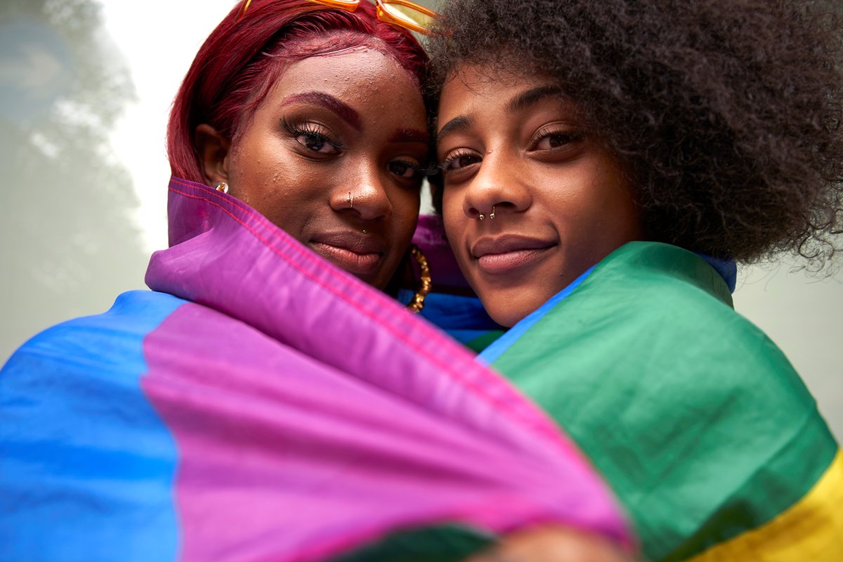 Two women wrapped in Pride flag.