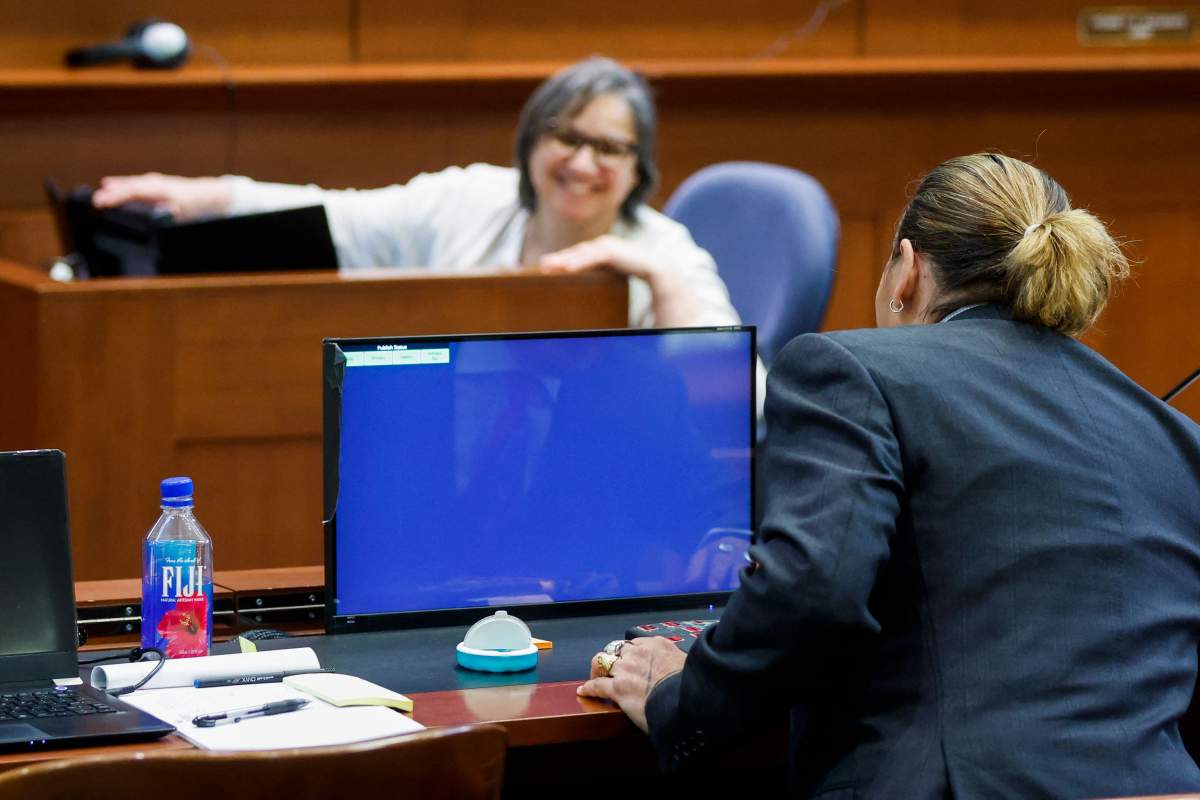 Actor Johnny Depp chats with the court stenographer during a break amid his defamation trial against his ex-wife Amber Heard, at the Fairfax County Circuit Courthouse in Fairfax, Virginia, April 27, 2022.