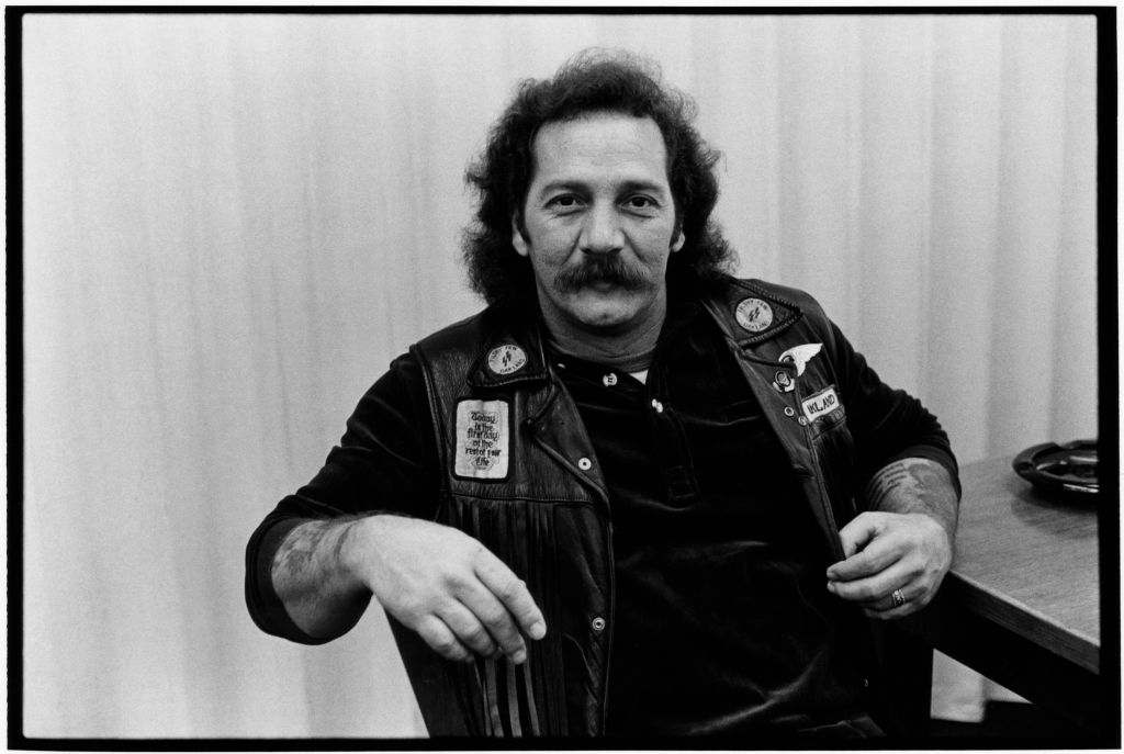 Portrait of American biker and founding member of the Oakland chapter of the Hells Angels Sonny Barger (born Ralph Barger) as he sits at a table, San Francisco, California, January 1979.