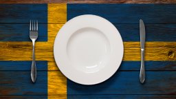 A Swedish flag printed on a table with an empty place setting on top.