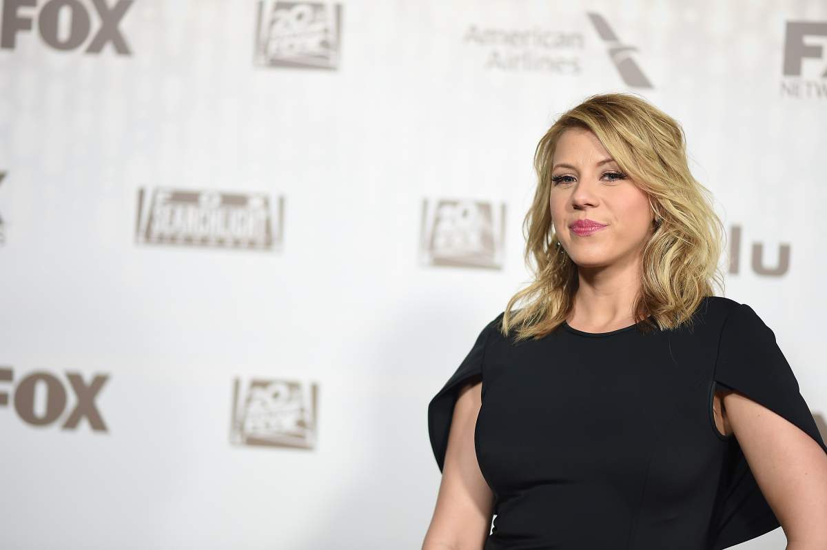 Jody Sweetin appears on a red carpet wearing a black dress.