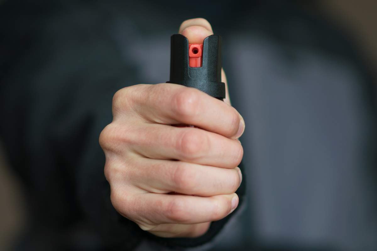 A close up of a hand holding pepper spray.