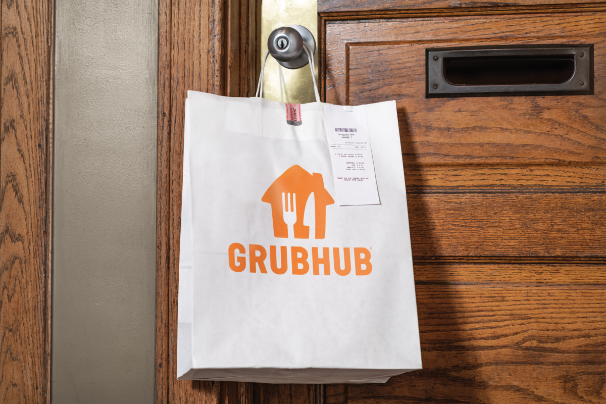 A food delivery bag is seen hanging from a doorknob.