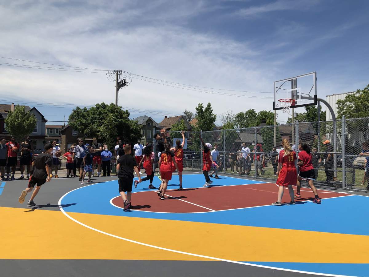 Youth from Bernie Custis Secondary School and the Eva Rothwell Centre play the inaugural game of basketball on the new court.