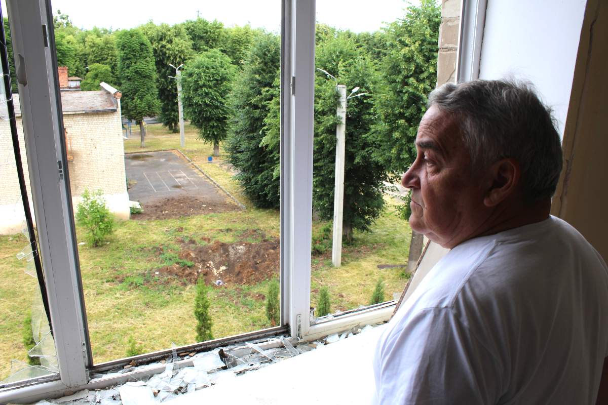 School director Oleksandr Gryanik looks out the window of a bomb-damaged school in Kharkiv, Ukraine, on June 22.