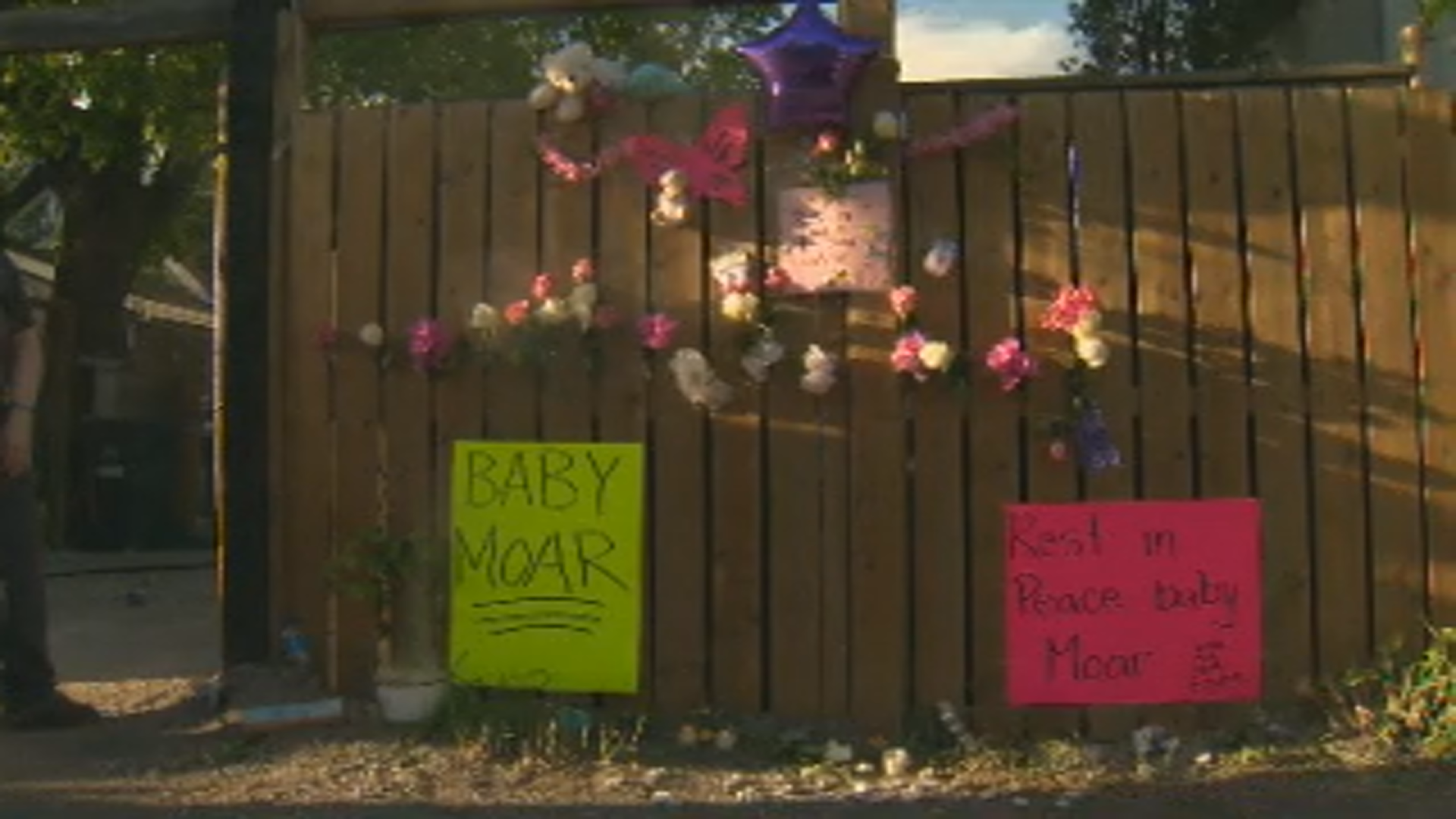 Flowers and signs posted near the site of where an infant was found in a garbage bin.