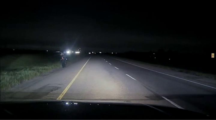 An RCMP officer is seen carrying a baby that had been in a vehicle that was stolen near Strathmore, Alta., on June 4, 2022.