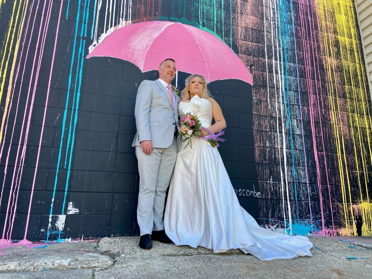 Newlyweds Stasha and Jason Vollman stand in front of an Instagram wall in Edmonton, Alta. on Saturday, June 11, 2022.