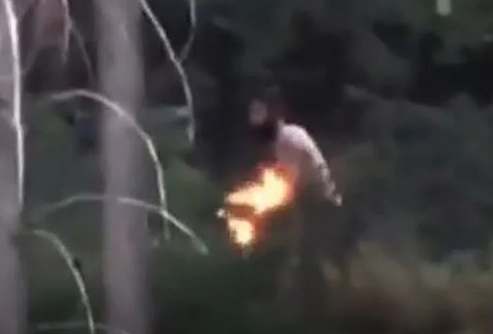 The video was posted to Facebook and shows a shirtless man walking along a steep, bush-covered hill behind a home in West Kelowna. 