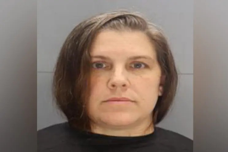 Caroline Dawn Pennington, 47, is seen wearing a black shirt against a grey wall in her mug shot. She has chin-length brown hair.