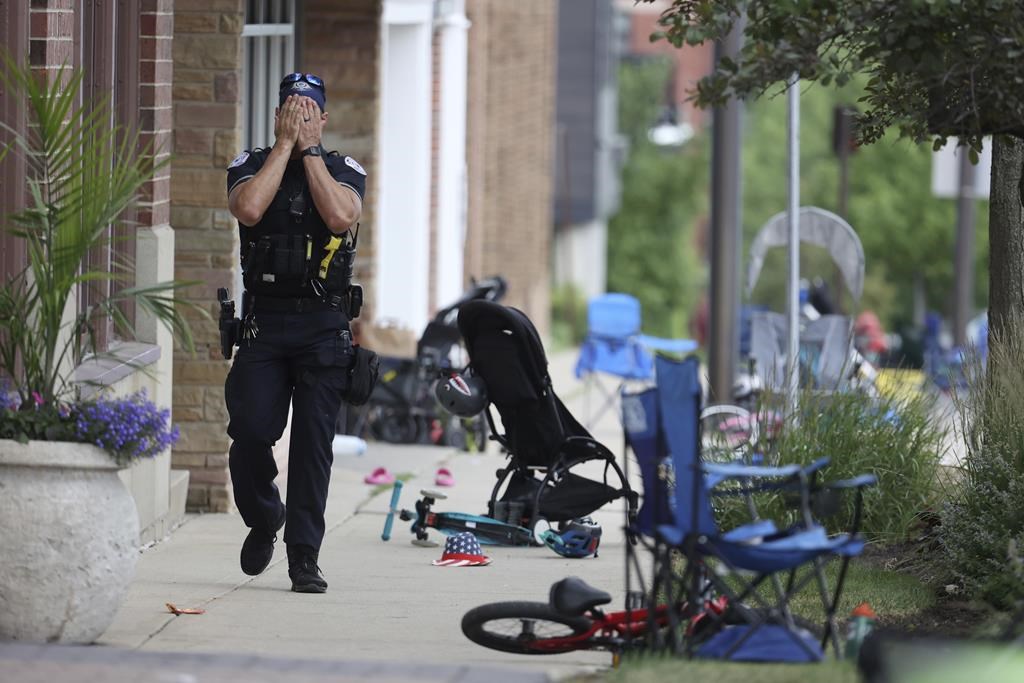 A Lake Forest, Ill., police officer walks down Central Ave in Highland Park, Ill., on Monday, July 4, 2022, after a shooter fired on the northern suburb's Fourth of July parade.