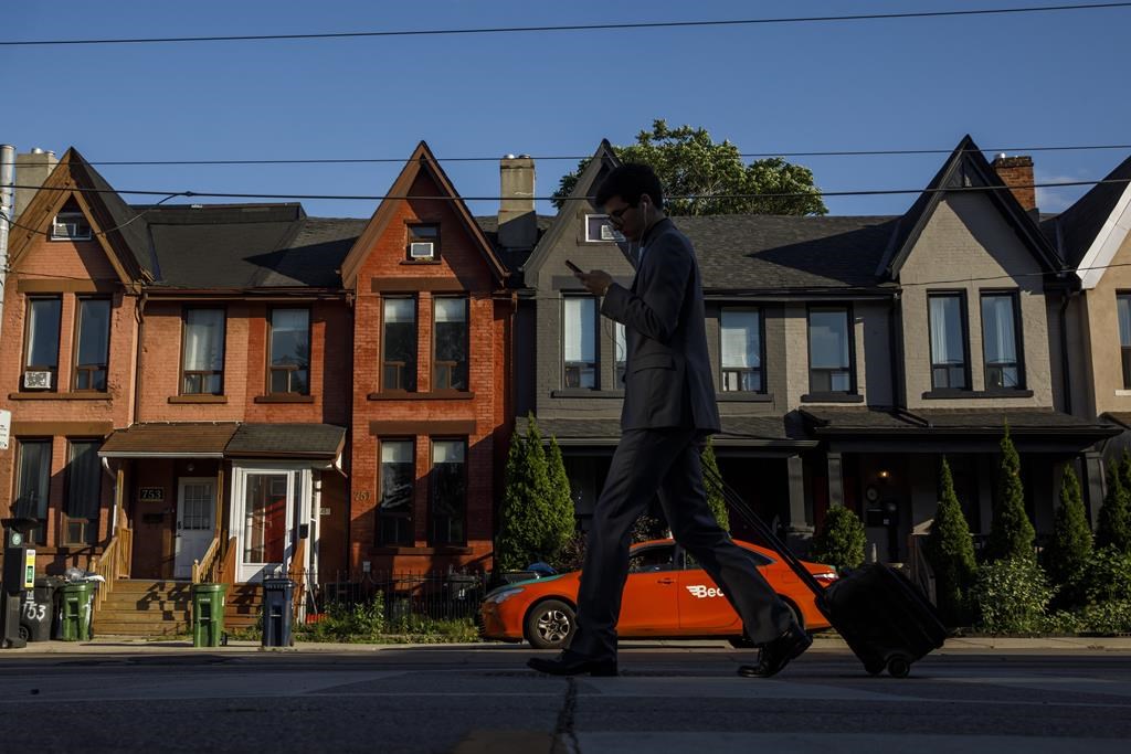 A person walks by a row of houses in on Tuesday July 12, 2022. Multigenerations living under one roof is becoming increasingly common, Statistics Canada's latest tranche of census data revealed Wednesday.