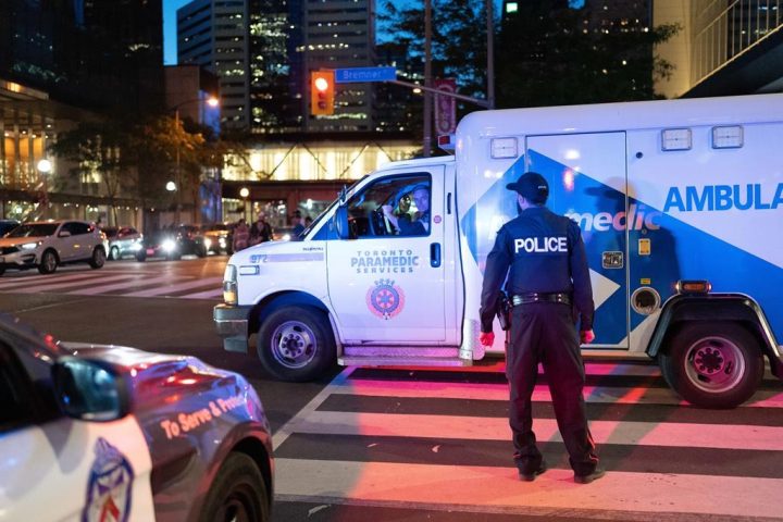 An ambulance moves past a member of the Toronto Police in downtown Toronto on Saturday July 16, 2022. 