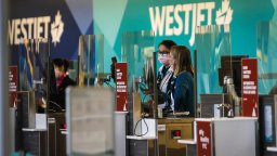 Westjet employees wearing masks wait for passengers at the Calgary Airport in Calgary, Alta., Friday, Oct. 30, 2020.