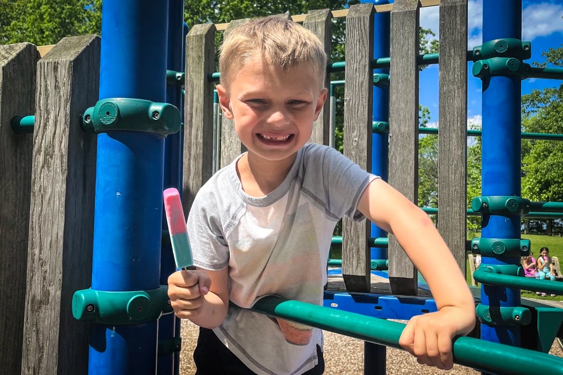 8-year-old Cooper Roberts holding a popsicle on a park play structure.