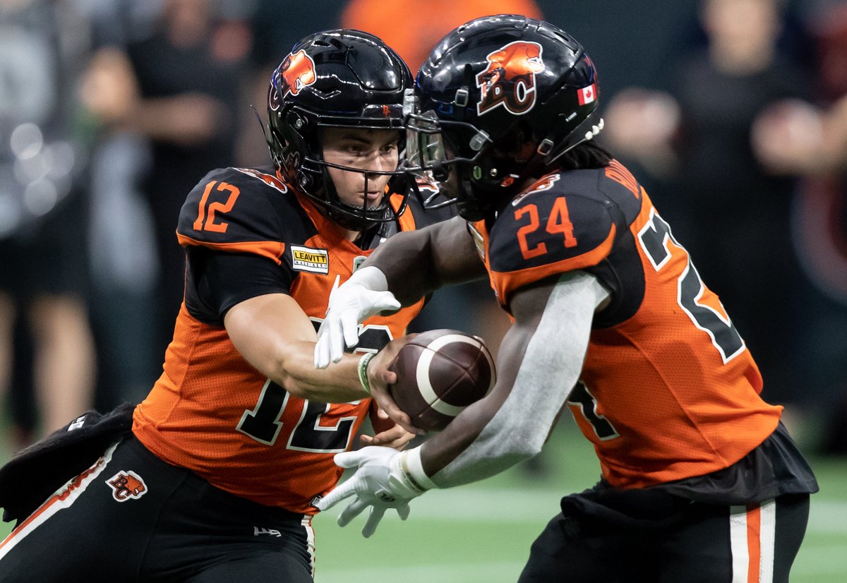 B.C. Lions quarterback Nathan Rourke hands off to James Butler during CFL first-half action against the Hamilton Tiger-Cats in Vancouver on Thursday, July 21, 2022. 