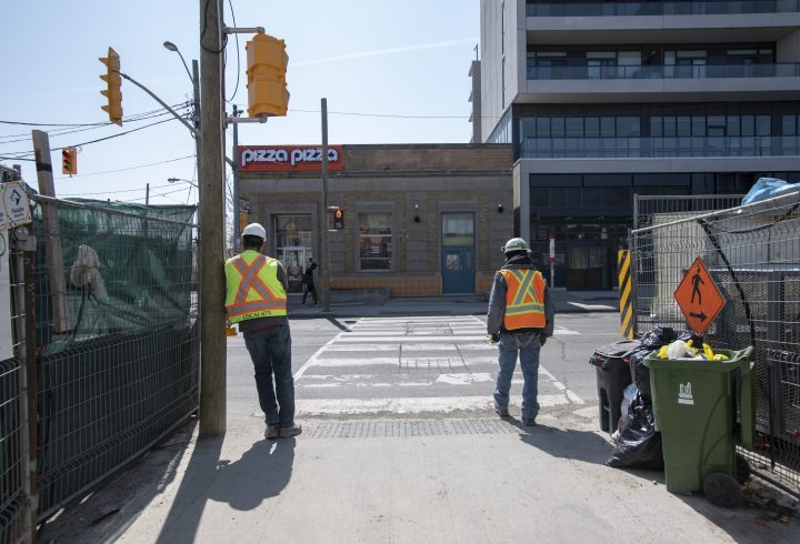 Construction workers wait to cross Eglinton Ave. West between Oakwood and Alameda Aves. on April 7, 2021. 
