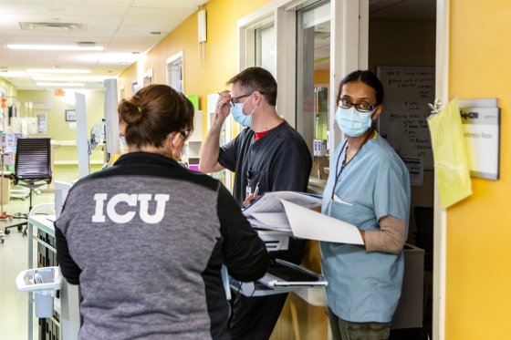 Health-care workers discuss a patient's progress in the ICU