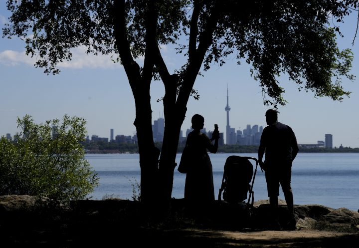 A family take pictures in the shade on a hot day in Toronto on Thursday, June 23, 2022. 