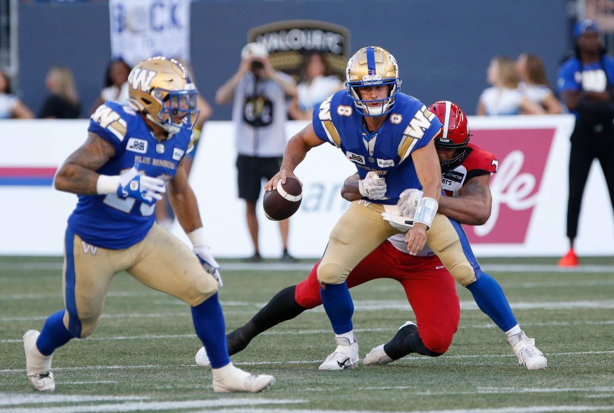 Winnipeg Blue Bombers quarterback Zach Collaros (8) gets sacked by Calgary Stampeders’ Mike Rose (41) during the first half of CFL action in Winnipeg, Friday, July 15, 2022.