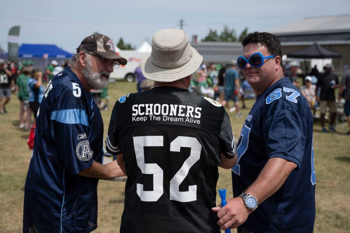 A CFL fan wearing an Atlantic Schooners jersey tailgates with Toronto Argonauts fans prior to the CFL Touchdown Atlantic game between the Toronto Argonauts and the Saskatchewan Roughriders at Acadia University in Wolfville, N.S., Saturday, July 16, 2022. The Schooners were to join the CFL in the 1980s but never played a game because funding could not be secured for a stadium. THE CANADIAN PRESS/Darren Calabrese