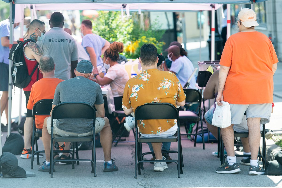 People wait to receive a monkeypox vaccine at an outdoor walk-in clinic in Montreal, Saturday, July 23, 2022. Tourists are among those lining up to get monkeypox vaccines in Montreal, as the World Health Organization declares the virus a global health emergency. THE CANADIAN PRESS/Graham Hughes