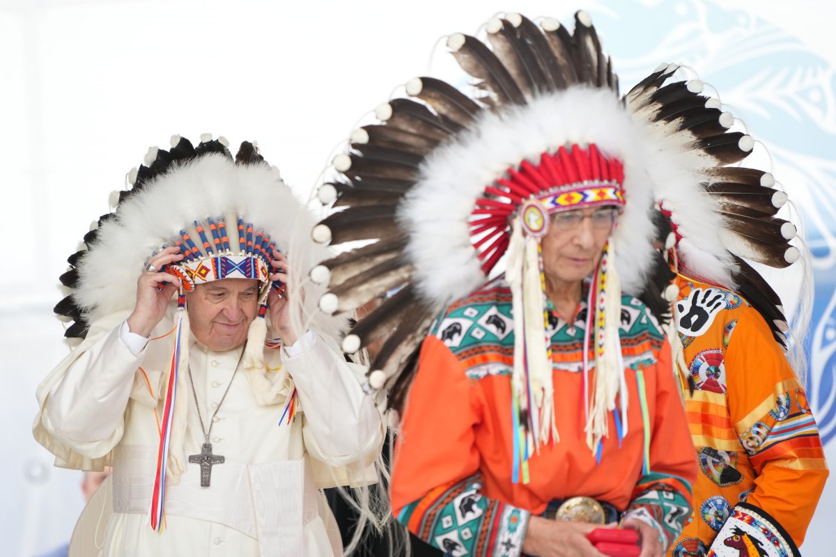 Pope Francis adjusts a traditional headdress he was given after his apology to Indigenous people during a ceremony in Maskwacis, Alta., as part of his papal visit across Canada on Monday, July 25, 2022.
